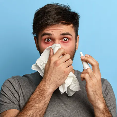 Uma imagem de um homem com alergias a segurar um lenço de papel no nariz