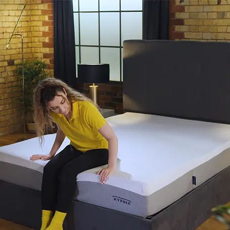 Person sitting on the edge of the mattress.