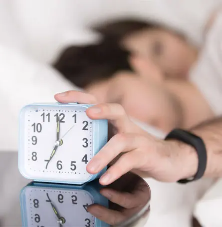 An image of a man turning off his alaram clock.