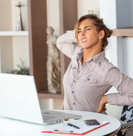 An image of a woman sitting at a desk with an injured back